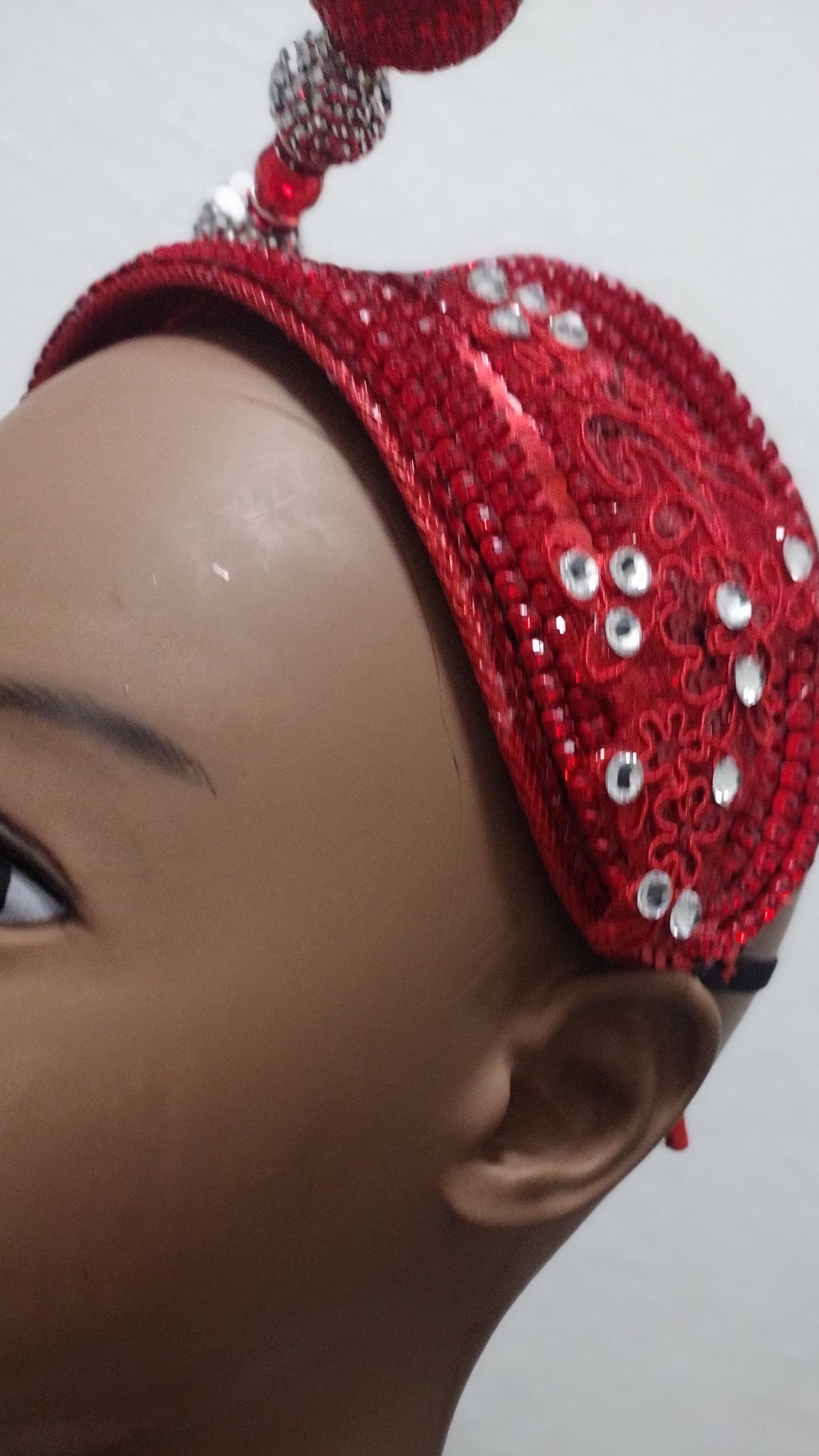 Close up of a mannequin wearing the red hat fascinator from a side veiw.
