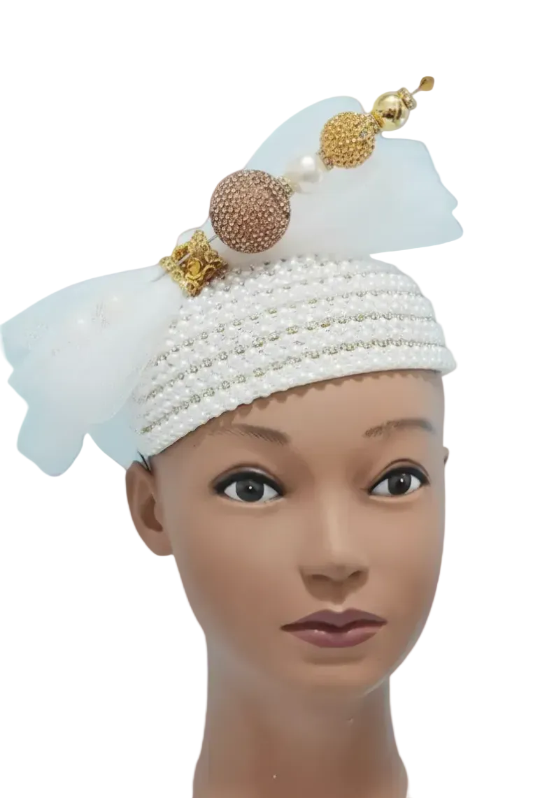 Mannequin head wearing a decorative white headwrap with pearls and gold accents on a plain background