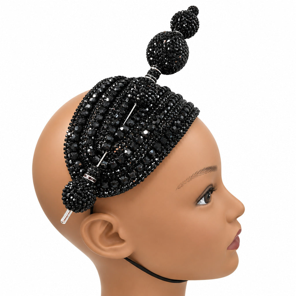 A black beaded headpiece with three decorative buns and silver rhinestone accents, displayed on a mannequin head against a white wall.