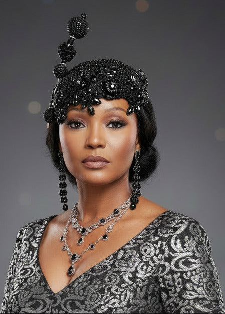 A black beaded and rhinestone fascinator headpiece displayed on a mannequin head against a white textured wall.