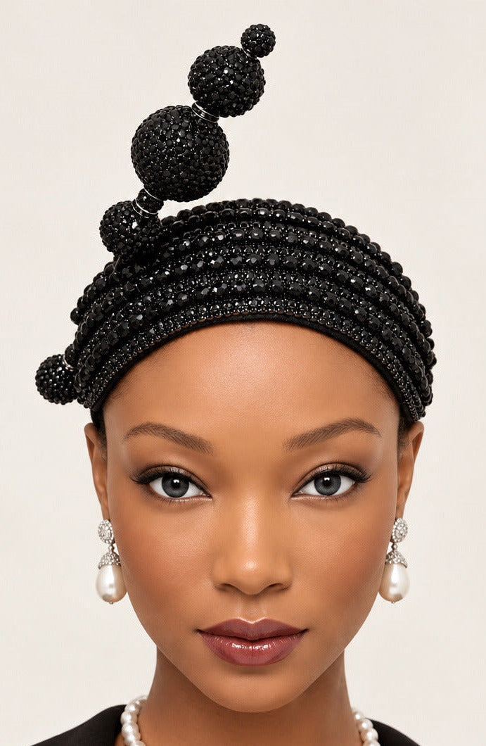 A black beaded headband with three vertical beaded loops and small side beads, displayed on a mannequin head against a plain white wall.