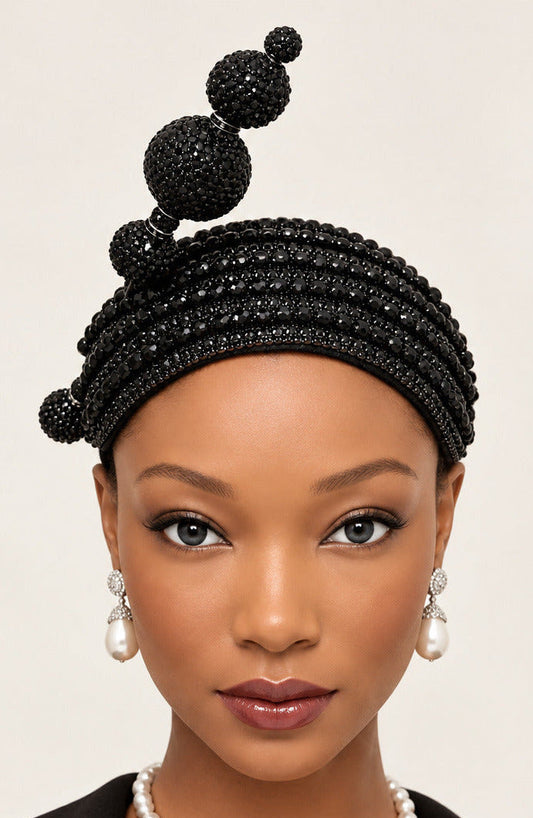 A black beaded headband with three vertical beaded loops and small side beads, displayed on a mannequin head against a plain white wall.